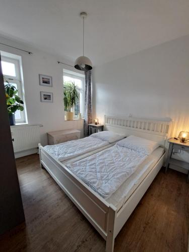 a large white bed in a bedroom with two windows at Deutsches Haus Apartments in Lohme