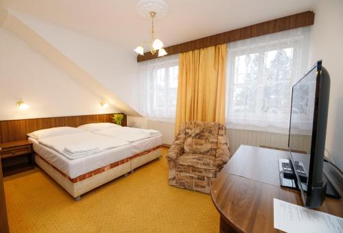 a bedroom with a bed and a desk and a tv at Penzion Pomnenka in Luhačovice