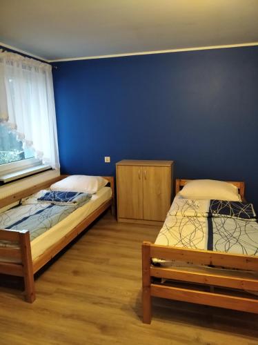 2 camas en una habitación con una pared azul en Pokoje Gościnne LaMa Gołuchów en Gołuchów