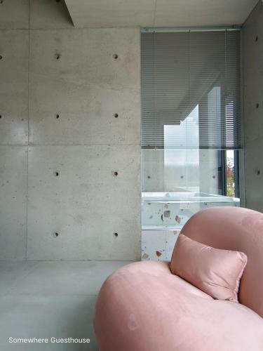 a pink chair in a room with a wall at Penghu Somewhere Guesthouse 澎湖嶼光角落民宿 in Magong