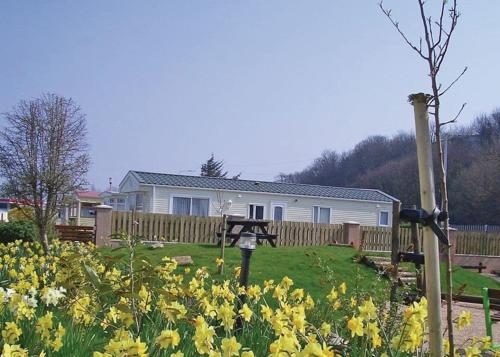 a house with a fence and flowers in a yard at Silver Birch Caravan Park in Talacre