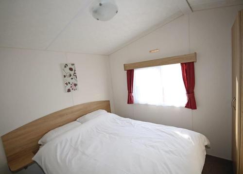a bedroom with a white bed and a window at Silver Birch Caravan Park in Talacre