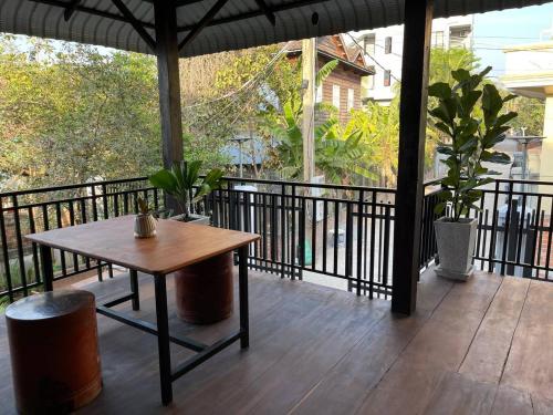 a patio with a table and a balcony with plants at Roya Khmer House in Siem Reap