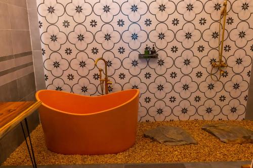 an orange tub in a bathroom with a wall at Green Mountain Homestay in Ninh Binh