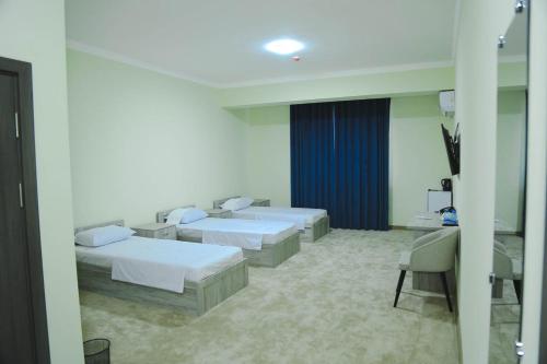 a white room with two beds and a chair at Гостиница Тумор in Shahrisabz