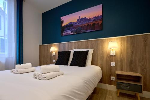 ein Schlafzimmer mit einem großen weißen Bett mit einem Gemälde an der Wand in der Unterkunft Le Faidherbe style Appart' Hôtel - WIFI gratuit - Parking Gratuit Calme et Lumineux in Nevers