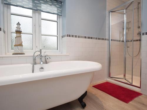a white bath tub in a bathroom with a window at 4 Bed in Corfe Castle 62985 in Worth Matravers