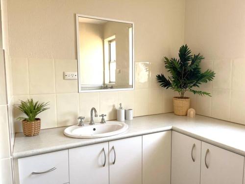 ein Bad mit einem Waschbecken und einem Spiegel in der Unterkunft Beautifully Styled 3 Bedroom Apartment in South Hedland