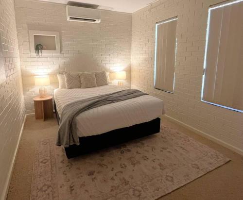1 dormitorio con 1 cama grande y 2 lámparas en Beautifully Styled 3 Bedroom Apartment, en South Hedland