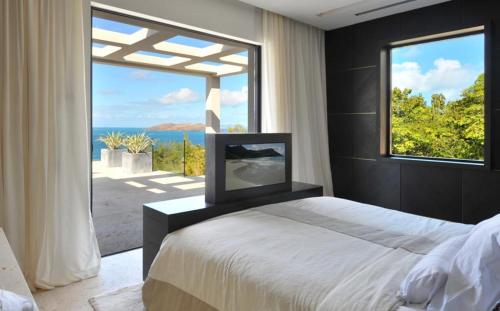 a bedroom with a bed and a large window at Luxury Vacation Villa 13 in Pointe Milou