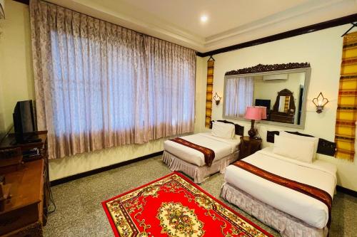 a hotel room with two beds and a mirror at Baan Rim Kwai Paerimnam Resort in Kanchanaburi
