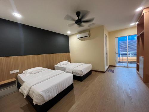 Un dormitorio con dos camas y un ventilador de techo. en Halo Hotel, en Semporna