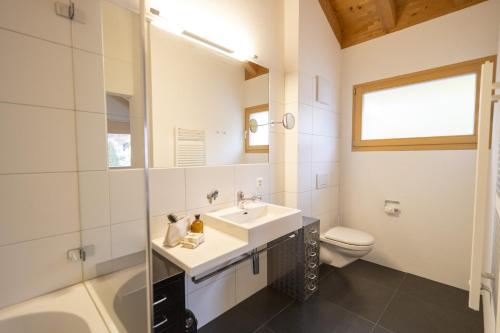 uma casa de banho com um lavatório e um WC em Chasa Capricornin em Scuol