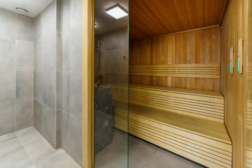 a walk in shower with wood paneling and a glass door at Koło Brzegu Apartment 48 in Kołobrzeg