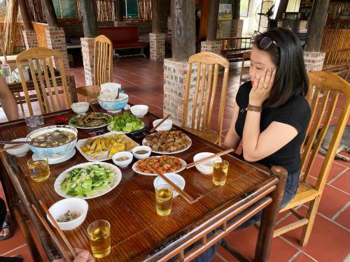 una mujer sentada en una mesa con platos de comida en Homestay Bách Thảo Tà Lùng, en Phục Hòa