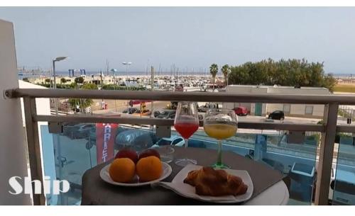 een tafel met twee glazen wijn en fruit op een balkon bij B&B Marina Sleep And Ship in Rodi Garganico