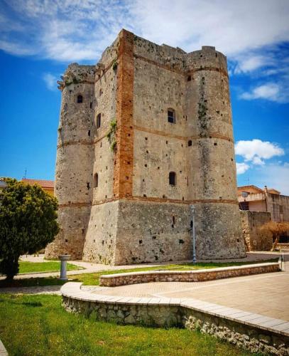 a large castle tower with a grassy field in front of it at House Torre Galea in Marina di Gioiosa Ionica