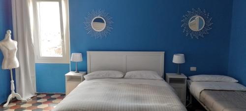 - une chambre bleue avec un lit et deux miroirs sur le mur dans l'établissement Borgo Santo Stefano, à Oschiri