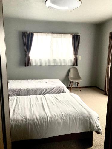 a bedroom with two beds and a window at Maison Petit Lapin メゾンプチラパン in Karuizawa