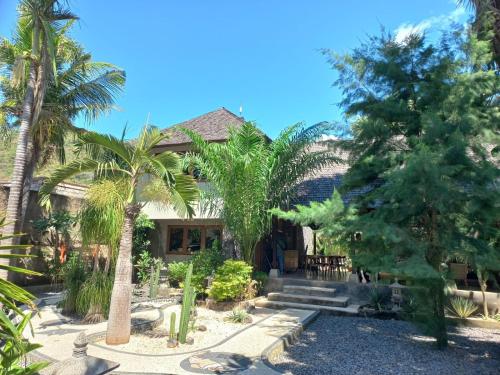 a house with palm trees in front of it at Villa del Mar Amed Bali in Amed