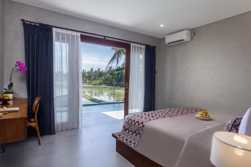Schlafzimmer mit einem Bett und einem Fenster mit Aussicht in der Unterkunft Ikada Villa by Pramana Villas in Ubud