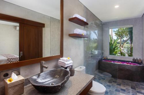 ein Badezimmer mit einem Waschbecken und einer Badewanne in der Unterkunft Ikada Villa by Pramana Villas in Ubud