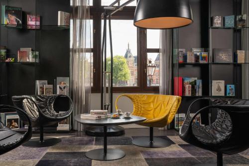 een kamer met stoelen, een tafel en een lamp bij art'otel amsterdam, Powered by Radisson Hotels in Amsterdam