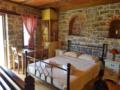 a bedroom with a bed and a stone wall at Likno in Avgonyma