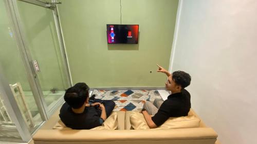 two young men sitting on a bed in a room at Safar Homestay Dekat JEC in Demangan