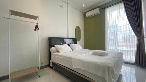 a bedroom with a bed with white sheets and a window at Safar Homestay Dekat JEC in Demangan