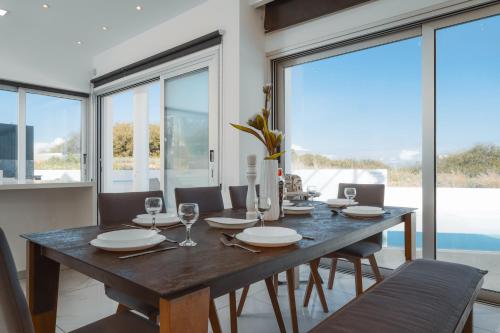 a dining room with a table and chairs and windows at Seaside Luxury Villa with Heated Pool in Paralimni