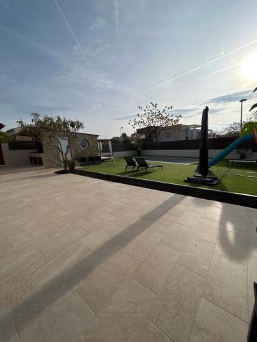 un patio con un parco con panchine e prato di Acogedora casa con piscina y 3 dormitorios a Vilanova i la Geltrú