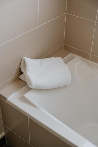 - une serviette blanche assise au-dessus d'une baignoire dans l'établissement Hotel-Restaurant La Caborne, à Limonest