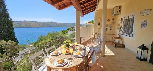 a table on a balcony with a view of the water at Jacuzzi, summer kitchen, gardens, 20m to beach - Villa Casa Plaza in Seget Vranjica
