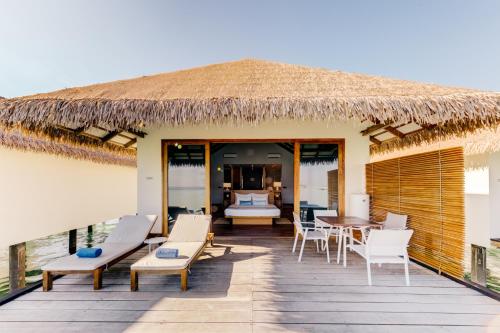 a resort deck with chairs and a table at Cinnamon Velifushi Maldives in Keyodhoo