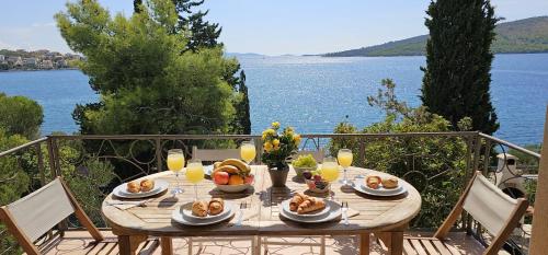 a wooden table with food and drinks and a view of the water at Jacuzzi, summer kitchen, gardens, 20m to beach - Villa Casa Plaza in Seget Vranjica