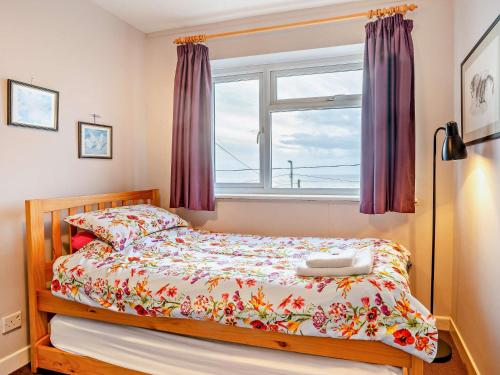 a bedroom with a bed and a window with purple curtains at 4 Bed in Ogmore-by-Sea 74236 in Saint Brides Major