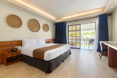 a hotel room with a bed and a balcony at Golden Sands Destination Resorts in Daanbantayan