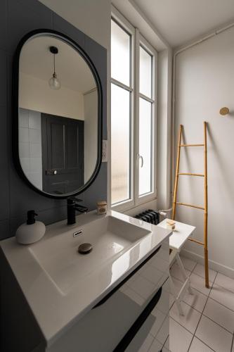 une salle de bain avec un lavabo blanc et un miroir dans l'établissement La maison Janisse - gîte en centre-ville avec jardin, à Limoges