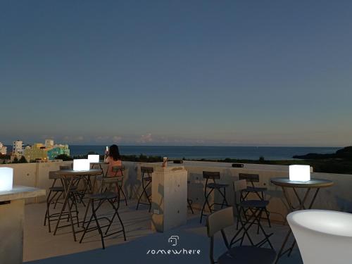 a woman sitting at a bar on a roof at Penghu Somewhere Guesthouse 澎湖嶼光角落民宿 in Magong