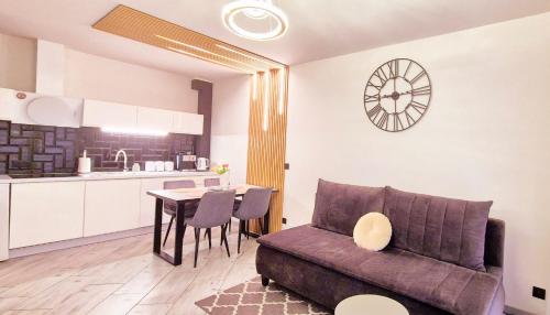a living room with a couch and a table and a kitchen at Apartament Black-White in Mielno