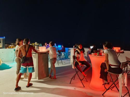 a group of people standing around a bar on a roof at Penghu Somewhere Guesthouse 澎湖嶼光角落民宿 in Magong