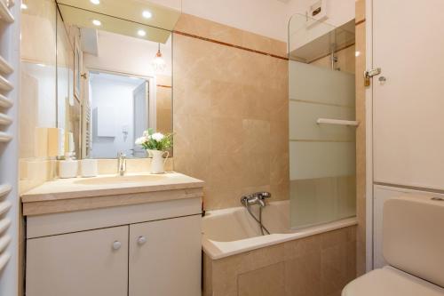 ein Badezimmer mit einem Waschbecken, einer Badewanne und einem WC in der Unterkunft Geranimus Versailles Charost in Versailles