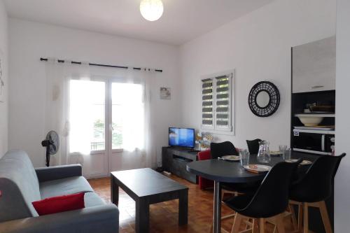 a living room with a couch and a table with chairs at T2 "Les Hameaux du Soleil" with pool and parking in Villeneuve-Loubet