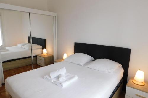 a bedroom with a white bed with a mirror at T2 "Les Hameaux du Soleil" with pool and parking in Villeneuve-Loubet