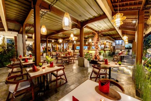 a restaurant with tables and chairs in a building at Anumana Ubud Hotel in Ubud
