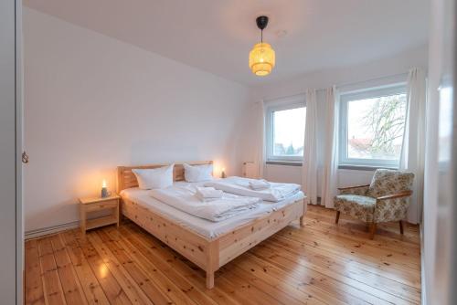a bedroom with a bed and a chair and two windows at Ferienhaus Maria 6 Schlafzimmer & Sauna in Ostseebad Koserow