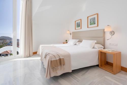 a white bedroom with a bed and a large window at Parque Santiago IV Official in Playa de las Americas