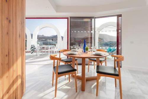 a dining room with a table and chairs and a balcony at Parque Santiago IV Official in Playa de las Americas