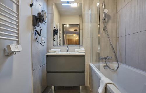 La salle de bains est pourvue d'une douche, d'un lavabo et d'une baignoire. dans l'établissement Résidence Prestige Odalys Le Mont d'Auron, à Auron